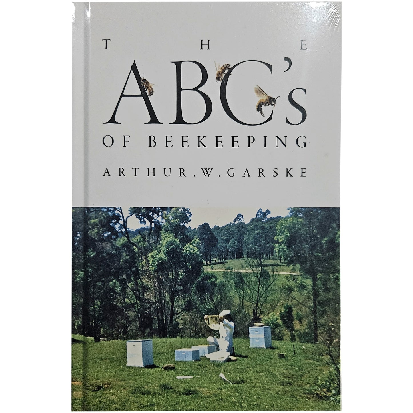 Book cover of 'The ABC's of Beekeeping' by Arthur W. Garske with a beekeeper and beehives on a grassy field.