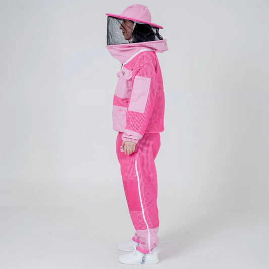Woman wearing OZ ARMOUR pink beekeeping jacket and trousers set with round veil hat, side view