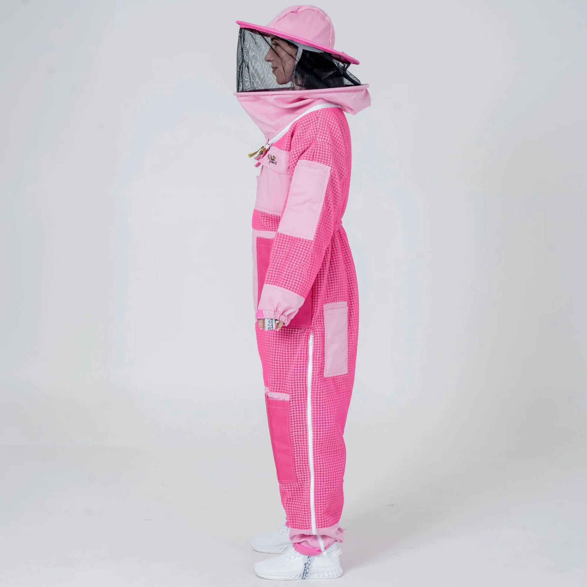 Side view of woman wearing 3 layer mesh pink beekeeping suit with round veil hat
