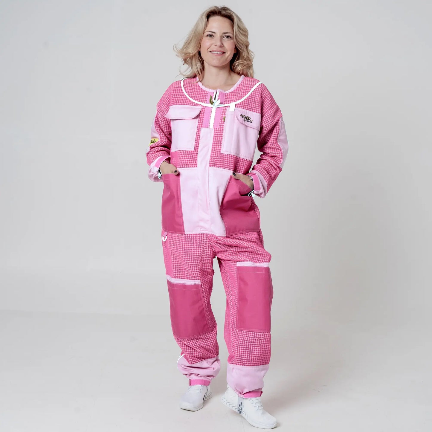Woman wearing 3 layer mesh pink beekeeping suit without veil, front view with hands in pockets