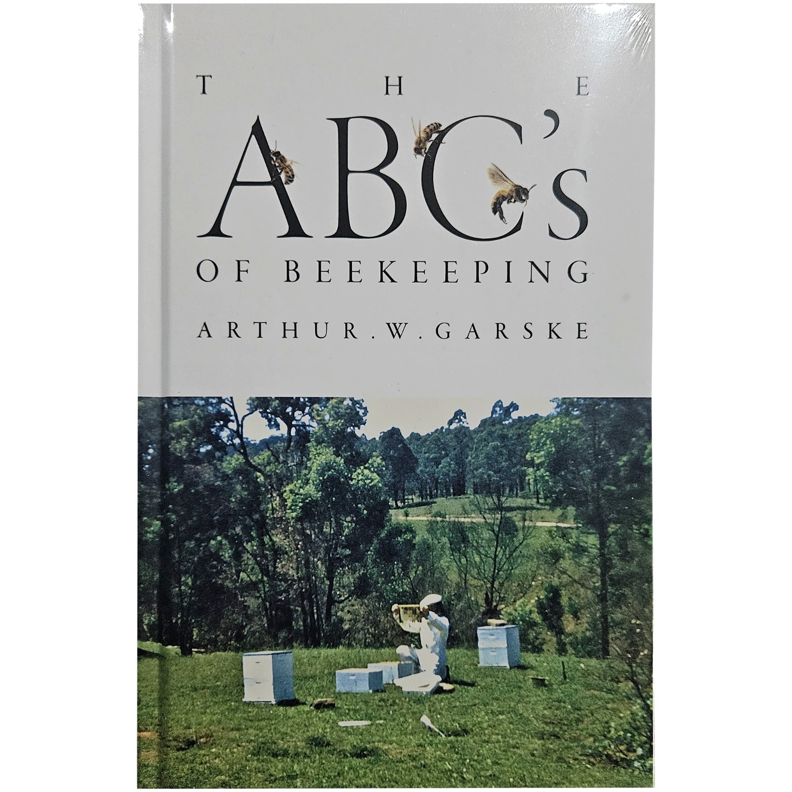 Book cover of 'The ABC's of Beekeeping' by Arthur W. Garske with a beekeeper and beehives on a grassy field.