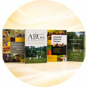 Four beekeeping books covering hive management, pests and diseases, and beginner guides, standing upright