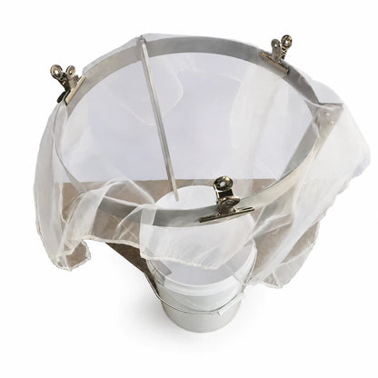 Stainless steel honey strainer mounted on stand above white bucket