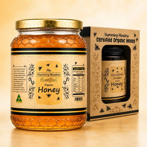 Humming Meadow Certified Organic Honey glass jar next to its kraft gift box with a viewing window