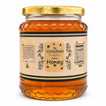 honey-glass-jar.webpGlass jar of Humming Meadow raw organic honey with honeycomb-textured base and gold lid on a white background