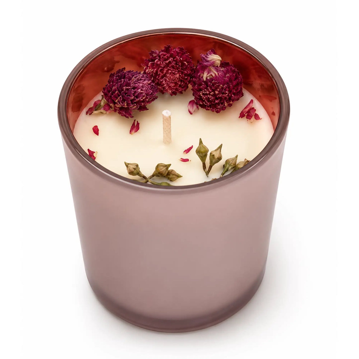 A single-wick candle in a translucent mauve glass jar filled with white wax, decorated with dried rose petals and green leaves on top, set against a plain white background.