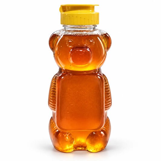 Honey bear squeeze jar filled with 700g of raw organic Bloodwood honey with a yellow flip-top cap on a white background
