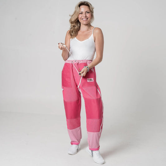 Woman wearing OZ Armour pink 3 layer mesh beekeeping trousers pulling the waist drawstring, front view
