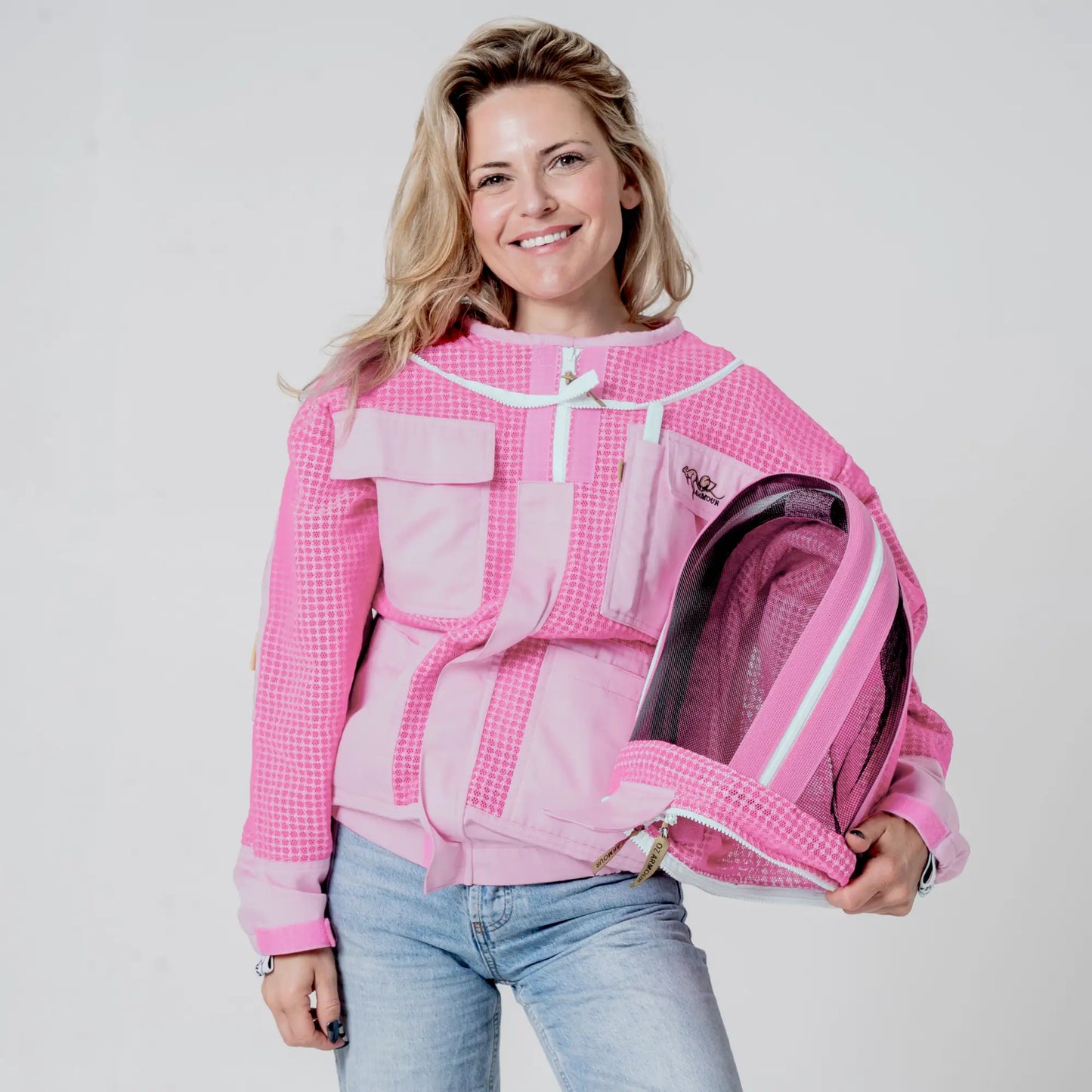 Woman holding open the unzipped fencing veil on the OZ ARMOUR pink beekeeping jacket