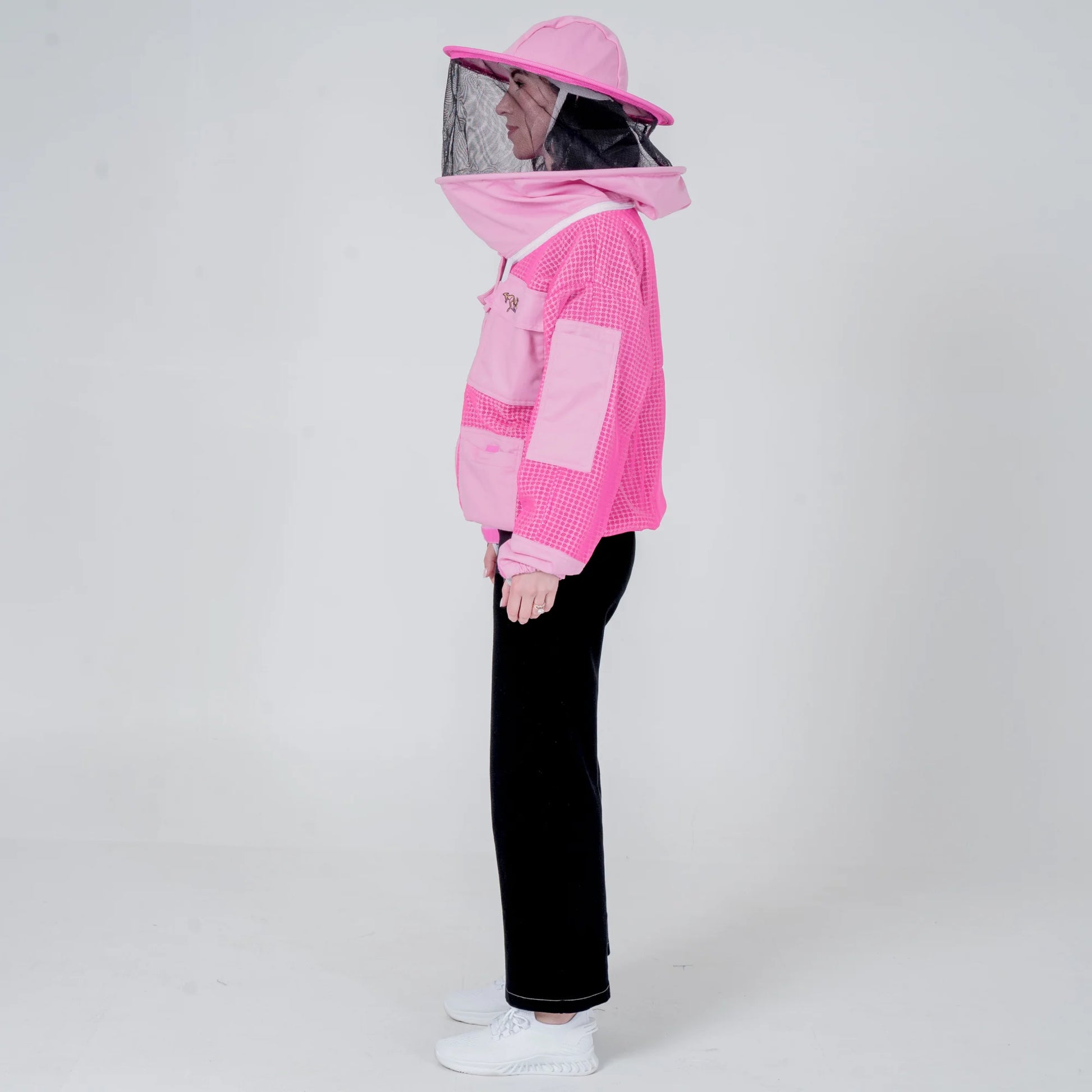 Woman wearing OZ ARMOUR pink beekeeping jacket with round veil hat, side view full body