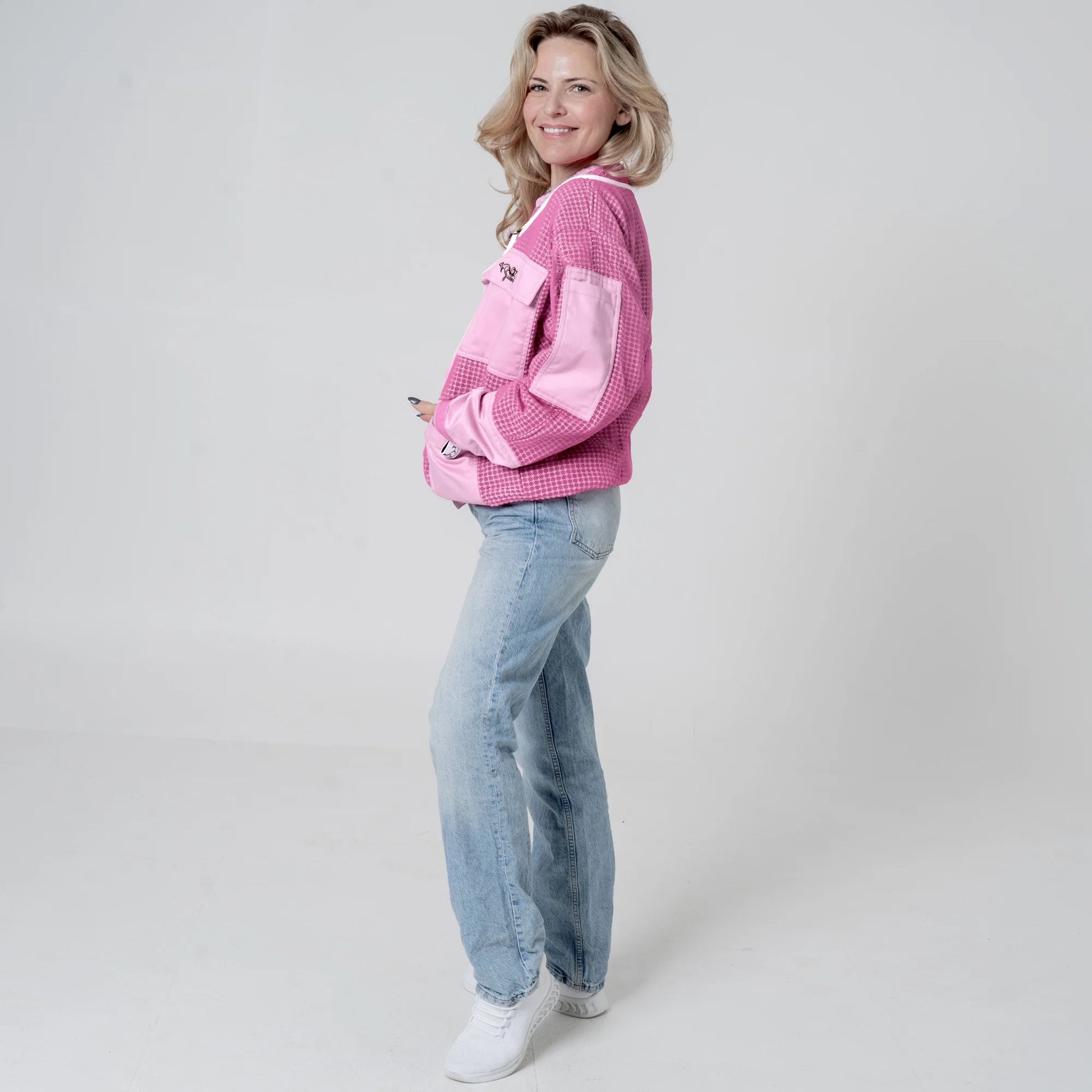 oman wearing OZ ARMOUR pink beekeeping jacket over jeans, side view full body
