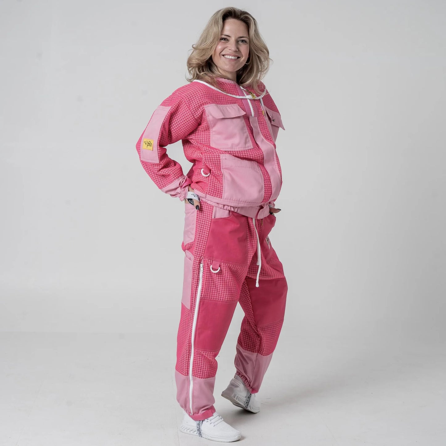 Woman wearing OZ Armour pink beekeeping jacket and trouser set, front pose with hand on hip

