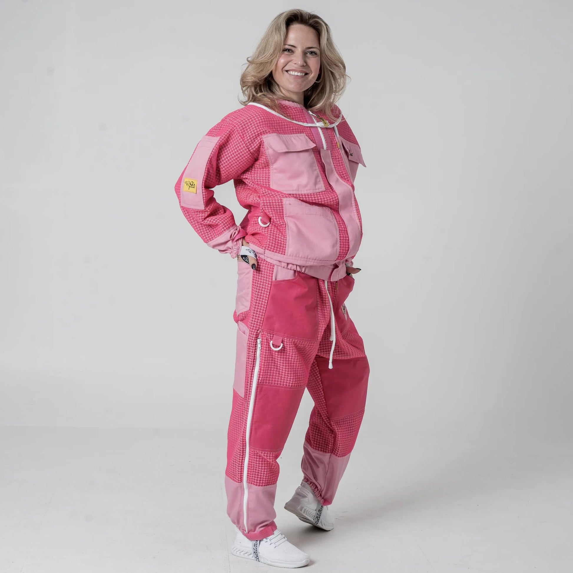 Woman wearing OZ Armour pink beekeeping jacket and trouser set, front pose with hand on hip
