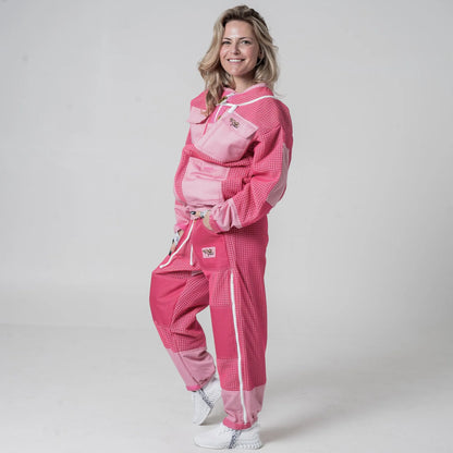 Woman wearing OZ Armour pink beekeeping jacket and trouser set with hood down, front view with hands in pockets
