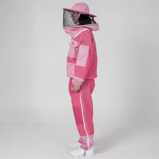 Woman wearing OZ Armour pink beekeeping jacket and trouser set with round hat veil hood up, side view

