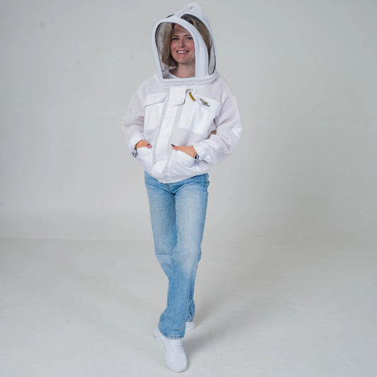 
Woman wearing OZ Armour white 3 layer beekeeping jacket with fencing veil hood up, full length walking front view
