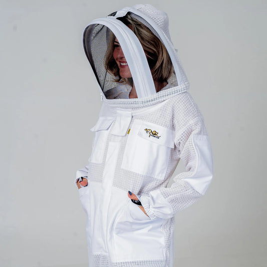 Woman wearing OZ Armour white 3 layer beekeeping suit with fencing veil hood up, side view with hands in pockets