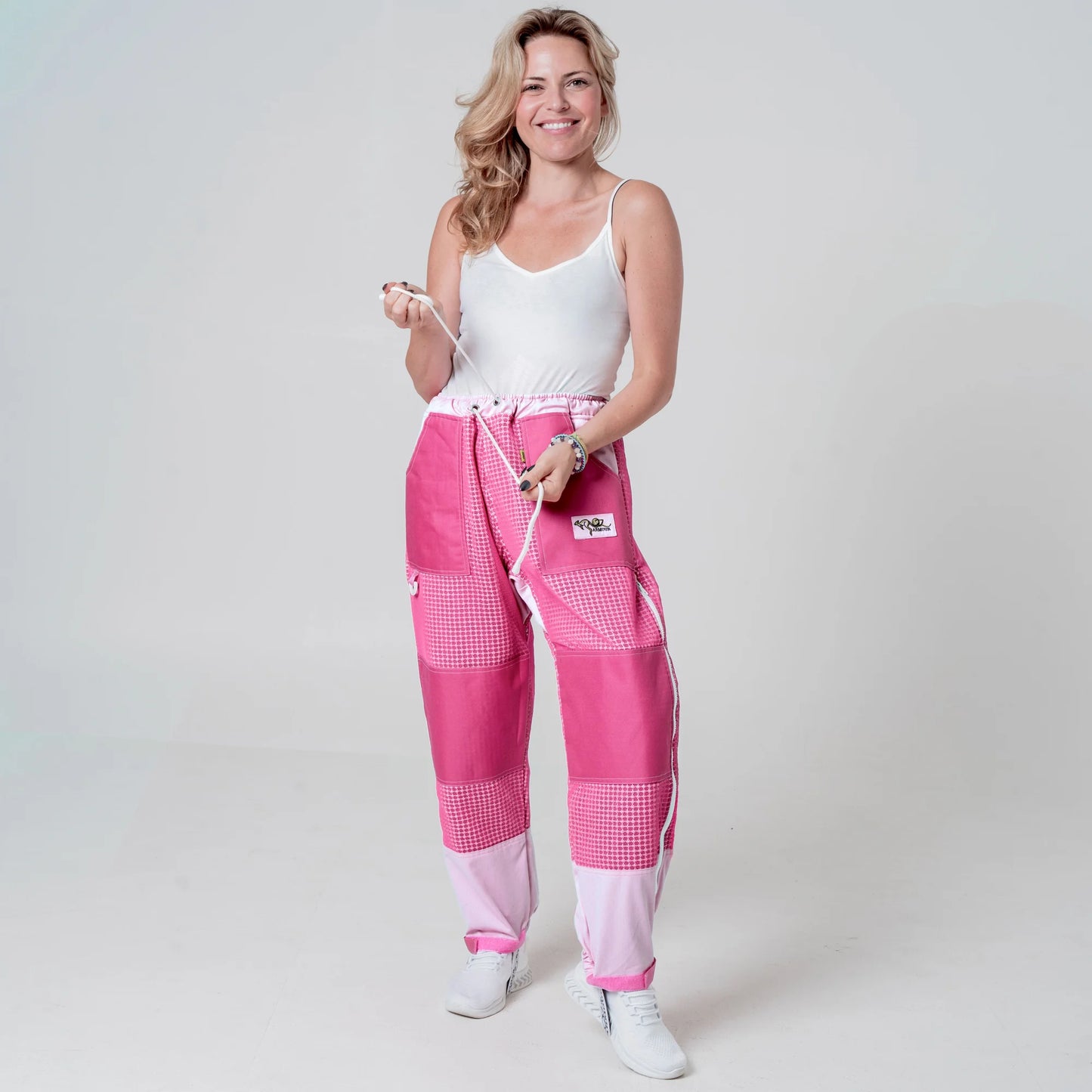 Woman wearing pink beekeeping trousers holding the waist drawstring, front view