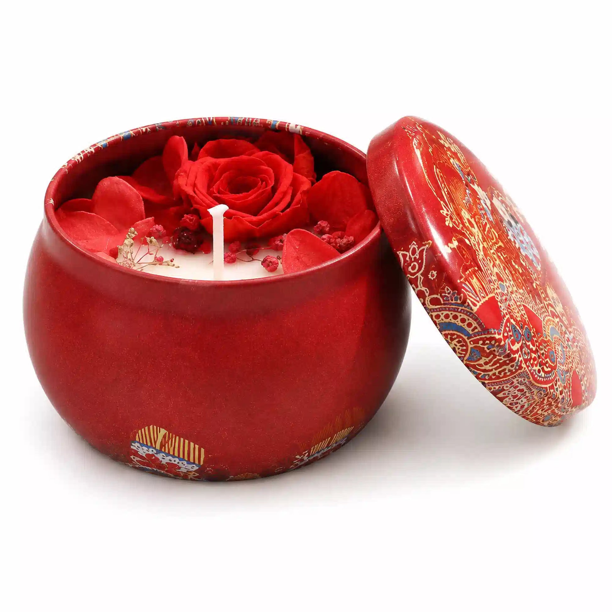 A red ceramic candle jar with a matching lid, featuring a red rose and red flower petals on the wax inside, set against a plain white background.