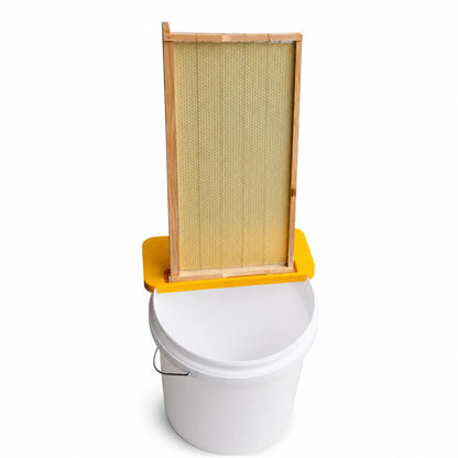 Beekeeping uncapping bench with honey frame and bucket