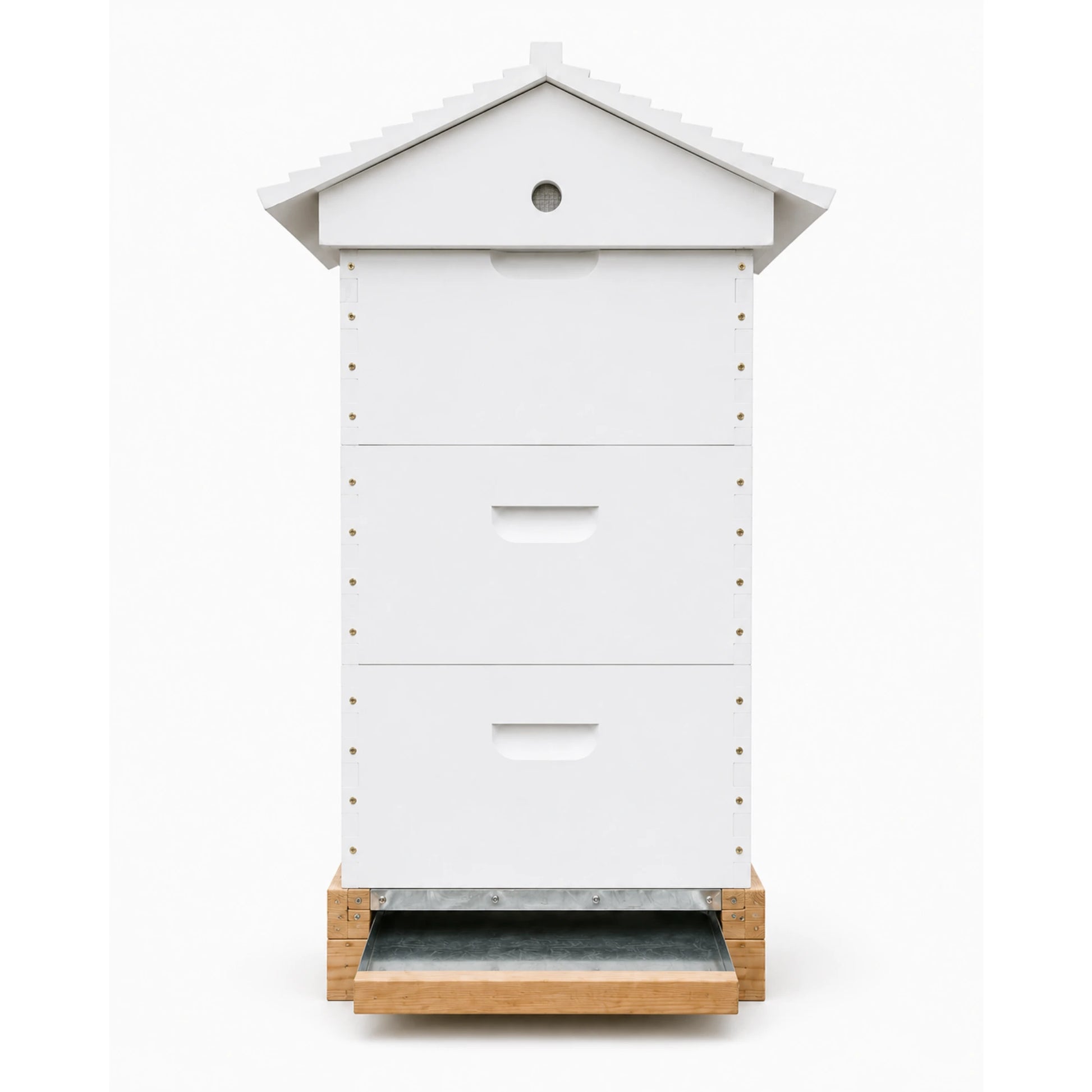 Side profile of a white three-box Langstroth beehive showing the sloped roof and metal pull-out bottom board on a wooden hive stand