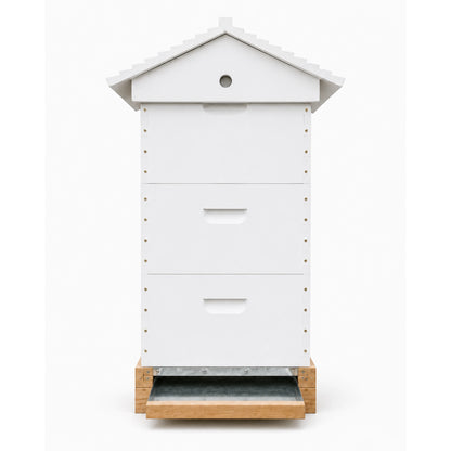 Side profile of a white three-box Langstroth beehive showing the sloped roof and metal pull-out bottom board on a wooden hive stand